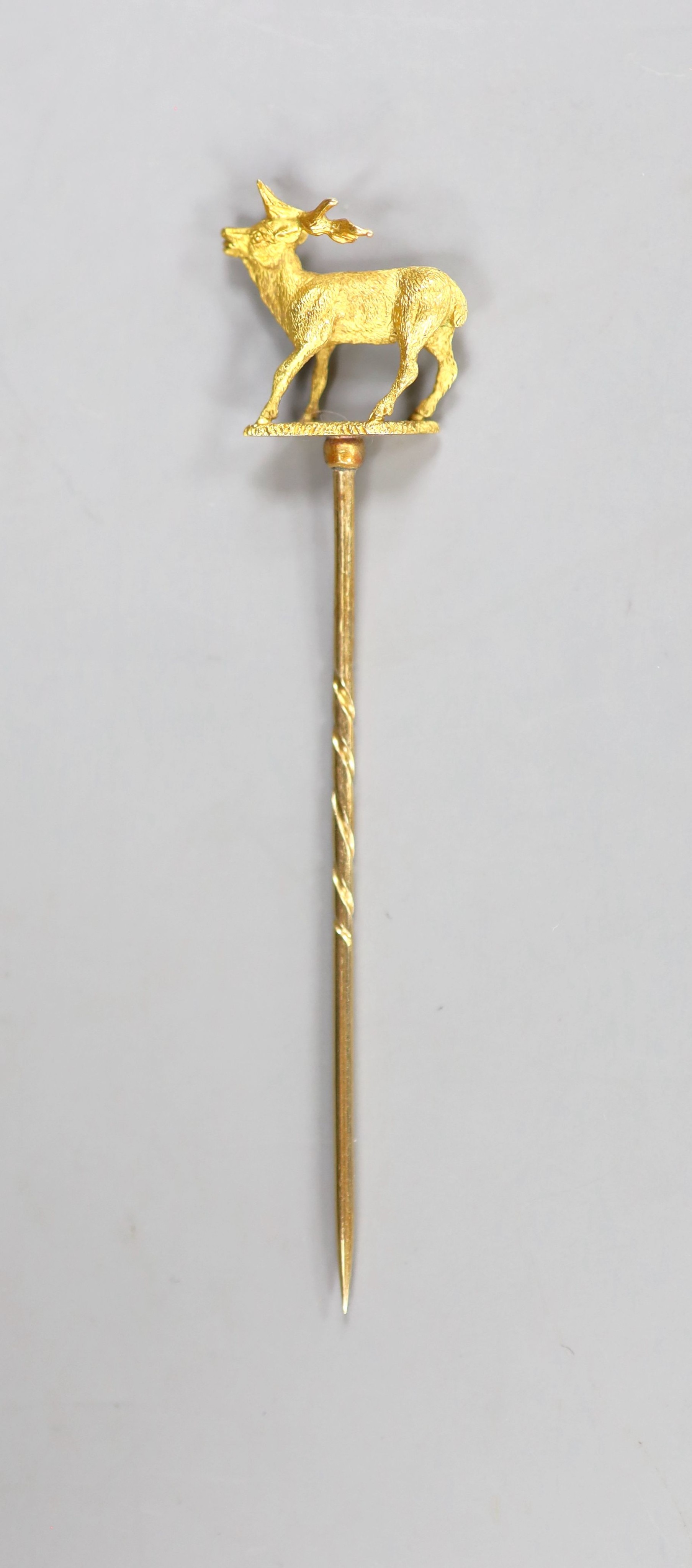 A cased early 20th century yellow metal stag stick pin, 77mm, 4.3 grams (a.f.).